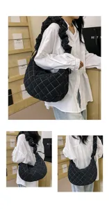 Detailansicht der schwarzen gesteppten Schultertasche mit Raffgurt und bunten Nähten für den täglichen Weg.