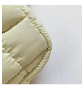 Detailed shot of quilted puffer cloud bag in light yellow, soft glossy padded texture.