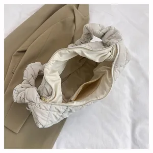 Detailansicht der beigen, gesteppten Puffer-Tasche mit Reißverschluss und weichem Innenfutter.