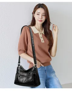 Detail view of black washed soft leather shoulder bag with multi pockets and zip compartments.