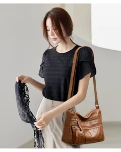 Detailed view of the multi-pocket soft leather shoulder bag worn by a model in casual wear.