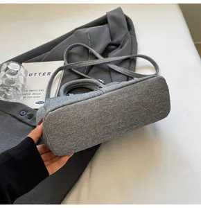 Gedetailleerd close-up van de hippe grijze denim handtas met fijne stoftextuur en sterke naden.