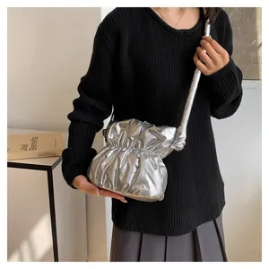 Silver puffy shoulder bag close-up detail, shiny pleated hobo bag fashion style.