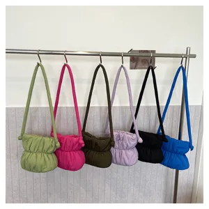 Detailed view of colorful nylon puffer shoulder bags featuring gathered pleated design on rack.