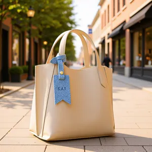 Beige PU leather tote bag with blue custom letter charm tag detail, elegant daily handbag accessory.