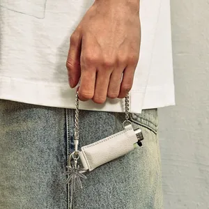 Detail shot of PU leather lighter sleeve with chain and leaf pendant, fashion accessory.