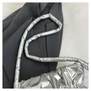 Close-up detail of silver metallic puffer shoulder bag with stylish pleated texture.