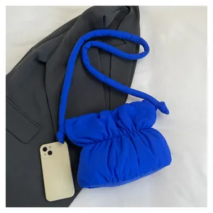 Blue puffy nylon shoulder bag detail view, stylish ruched design with jacket and phone props.