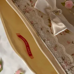Détail de trousse à crayons en dentelle florale avec nœud et perle pour papeterie.