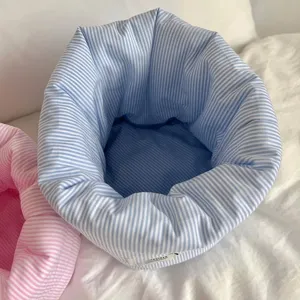 Gros plan détaillé de l'intérieur du panier de rangement de cosmétiques matelassé rayé.