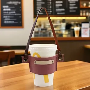 Dettaglio della custodia in pelle per tazza con design bicolore e cinturino regolabile.