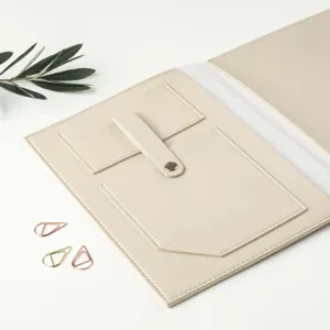 Detail view of beige PU leather trifold notebook folder interior pockets and snap button closure.