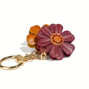 Vista dettagliata di un portachiavi a fiore in pelle con dettagli metallici dorati e petali.