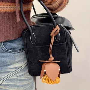 Sac à main en daim noir élégant avec pendentif gland de fleur en cuir marron et jaune pour femme.