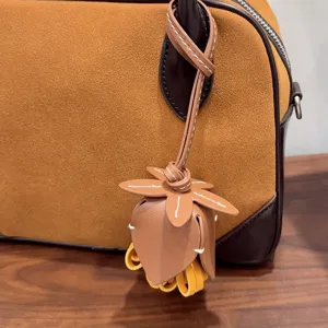 Gros plan detail pendentif sac fleur en cuir, accessoire decoration sac daim marron.