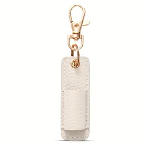 Detalle de primer plano del bolsillo portalápices de cuero blanco con llavero dorado.