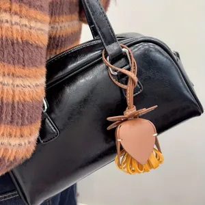 Détail de charm de sac en cuir fleuri chic, pendentif de sac à main pompon stylé pour femmes.