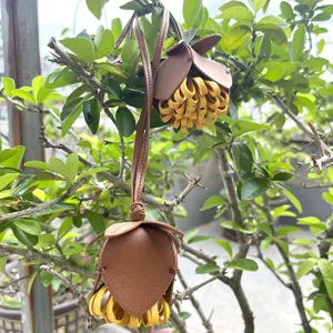 Breloque de sac fleur en cuir avec pétales marron et pampille frangée jaune.