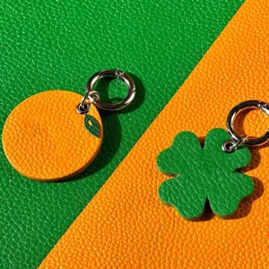 Detail shot of cute orange and four-leaf clover leather pet tags with metal rings.