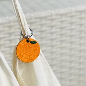 Orange leather pet tag with green leaf detail, cute puppy accessory and collar pendant charm.