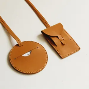 Set d'étiquettes de bagage en cuir marron, rondes et rectangulaires pour valise avec sangle.