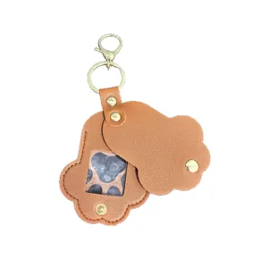 Brown leather pet memorial keychain detail, cute paw shape design with transparent photo window.