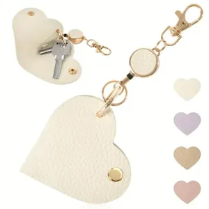 Estuche de cuero para llaves en forma de corazón con carrete retráctil y gancho dorado.
