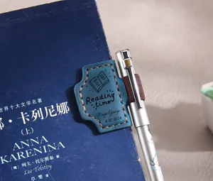 Gros plan sur le marque-page magnétique en cuir bleu avec passant pour stylo élastique sur livre.