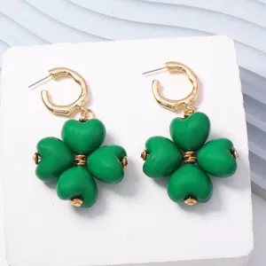Detalle en primer plano de pendientes de trebol con corazon verde, diseno metal.