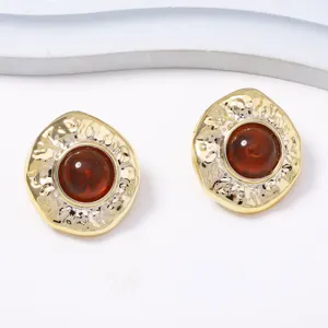 Detailaufnahme runder Vintage-Ohrringe aus strukturiertem Goldlegierung und braunem Harz.