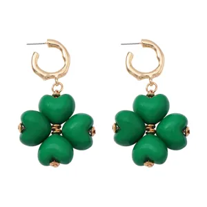 Primer plano detallado de pendientes colgantes de trébol de corazón verde con aro dorado.