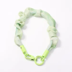 Vue détaillée de la sangle de porte-clés en tissu plissé vert clair et fermoir en métal.
