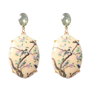Detail van ovale oorringen met traditionele bloemenprint en schitterend kristal.