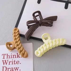 Detailed shot of large acrylic hair claw clips featuring elegant bow and braided chain designs.
