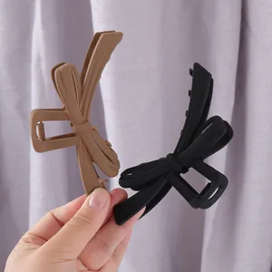 Large matte bow hair claw clip solid color shark clip elegant hair accessory detail view.