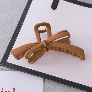Detail shot of matte brown bow hair claw clip, large acrylic shark clip for daily hair styling.