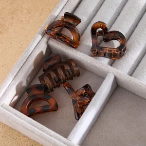 Detail view of brown tortoiseshell small hair claws, featuring multi-shape clips in a tray.