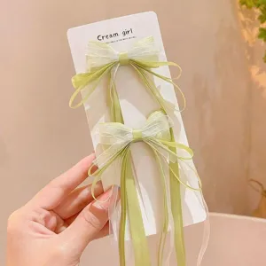 Close-up detail of cute green mesh bow hair clips with long streamers on card display.