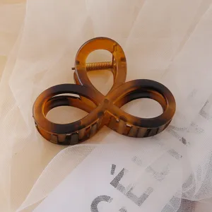 Brown tortoiseshell acrylic hair claw clip with stylish openwork design for daily hair styling.
