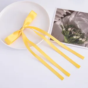 Yellow satin ribbon bow hair clip with long streamers for sweet girls elegant daily wear.