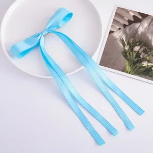 Light blue satin ribbon bow hair clip detail, featuring long streaming tails for elegant hairstyles.