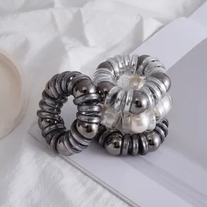 Vista dettagliata dell'elastico per capelli a spirale con perle eleganti e perline metalliche.