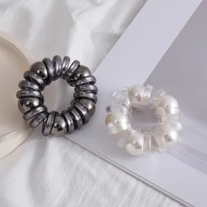 Primo piano dettagliato di eleganti elastici per capelli a spirale con perle decorativi.