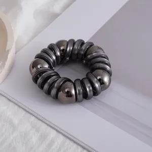 Dettaglio elastico per capelli a spirale metallica scura, con perle lucide per eleganti acconciature.