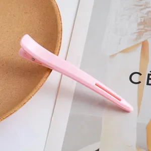 Detailed close-up of a pink salon hair clip, professional sectioning duckbill design for hair styling.
