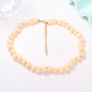 Primo piano della collana di perle cilindriche giallo pastello con chiusura in metallo.
