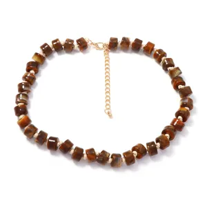 Primo piano della collana di perle marroni effetto tartaruga con catenella dorata.