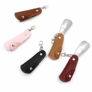 Portable folding shoe horn with leather case and keychain for convenient travel use.