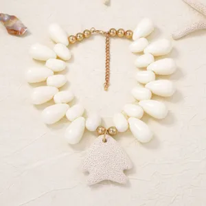 Detail shot of volcanic stone fish pendant necklace with white teardrop beads and golden chains.
