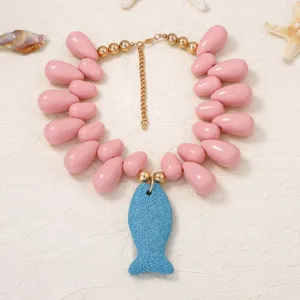 Detailed shot of bohemian ocean style beaded necklace with pink drops and blue fish pendant
